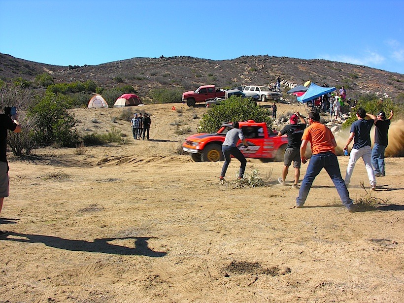 Spectators cheering on a trophy truck at the Baja 1000